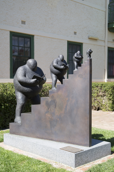 A bronze scupture depicting a staircase with four figures walking upwards.