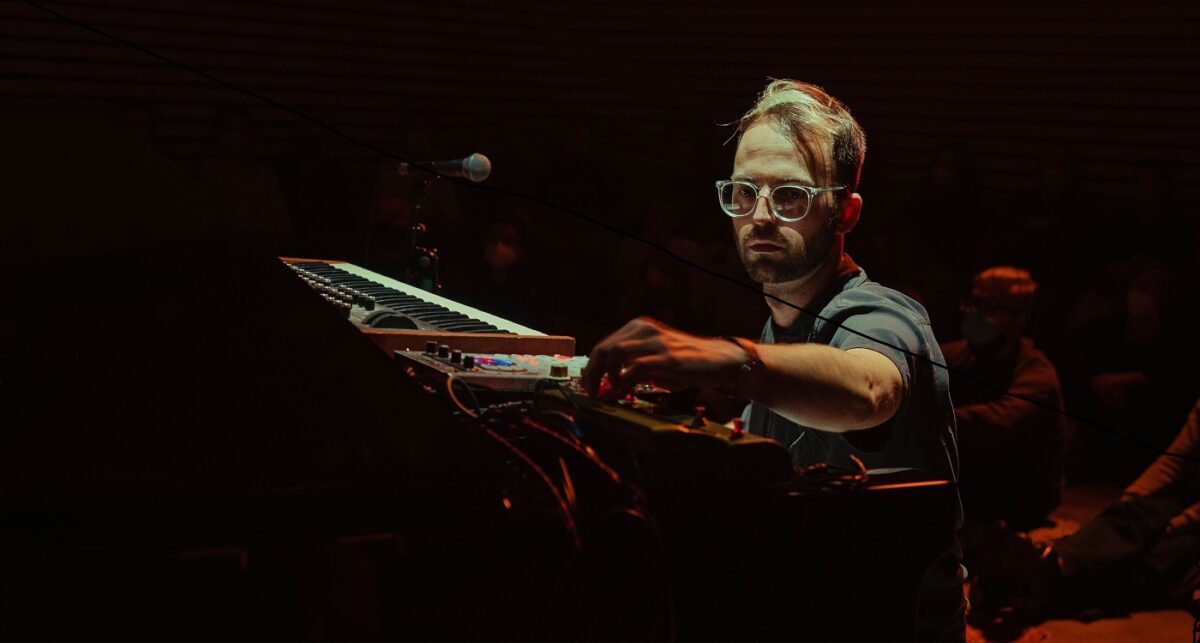 Man wearing glasses seated at a piano
