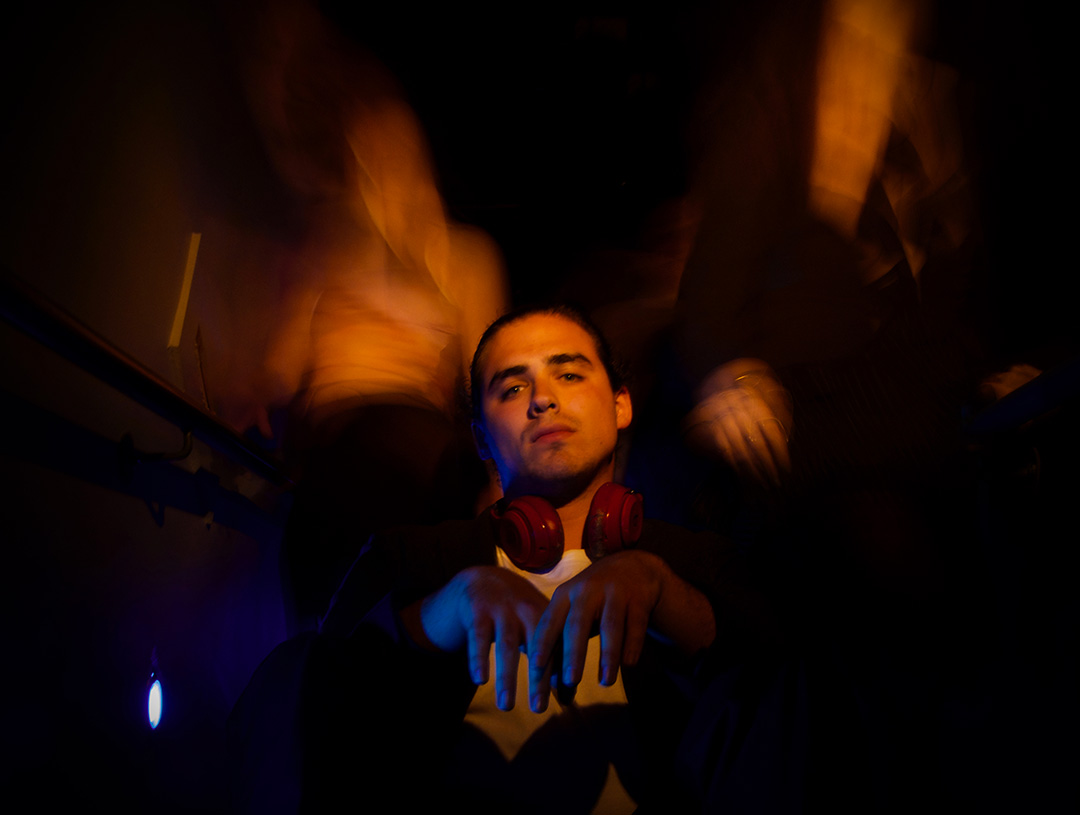 A teenage boy with headphones aropund his neck has his hands limply in front of him.