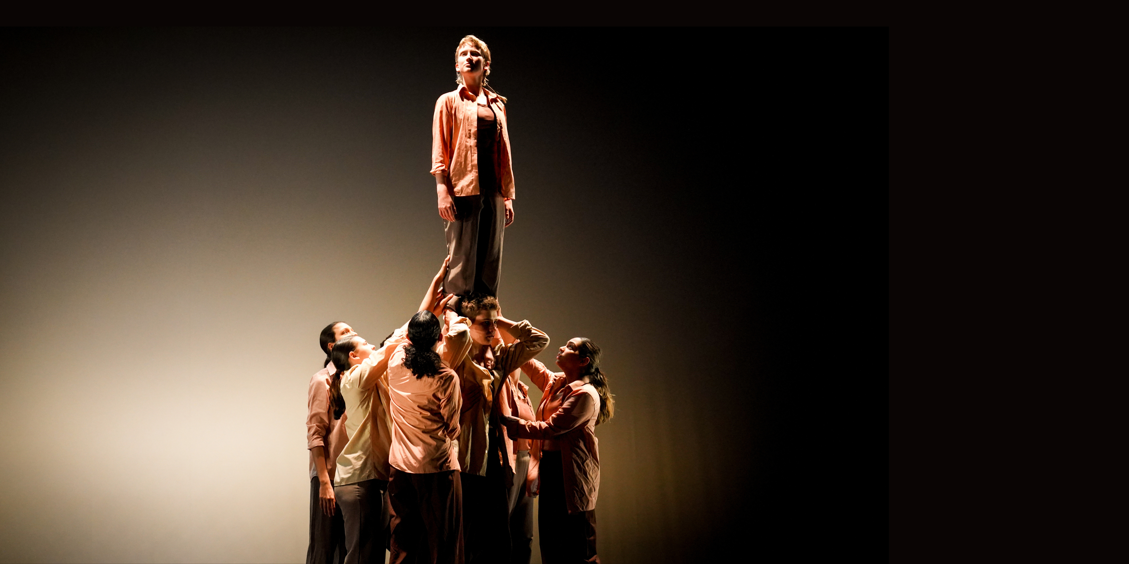 A group of dancers hold up a single dancer above them.